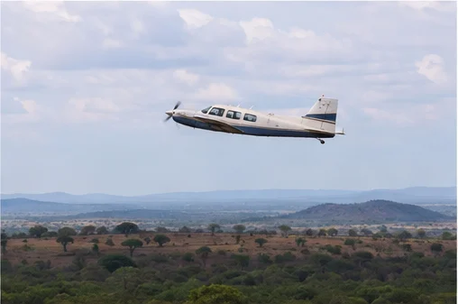 Light aircraft flying above East African savannah